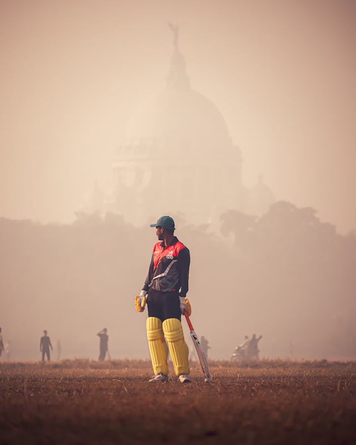 A man in a cricket uniform standing in front of a building